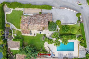 Vista aérea de uma propriedade com piscina, área de terraço e jardim ajardinado.