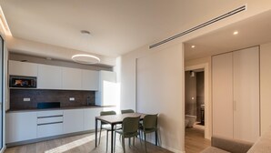Een moderne keuken met witte kasten, een eettafel met stoelen en een inbouwoven.