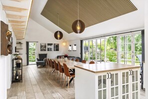 Eine moderne Küche mit einer großen Kochinsel, Holzboden und großen Fenstern.