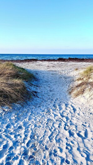 A sandy beach path leading to the ocean with footprints in the sand. - Modern holiday home with hot tub and nature (Vig)