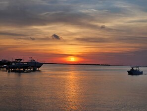 Ein Sonnenuntergang über ruhigem Wasser, mit Booten an einem Steg.