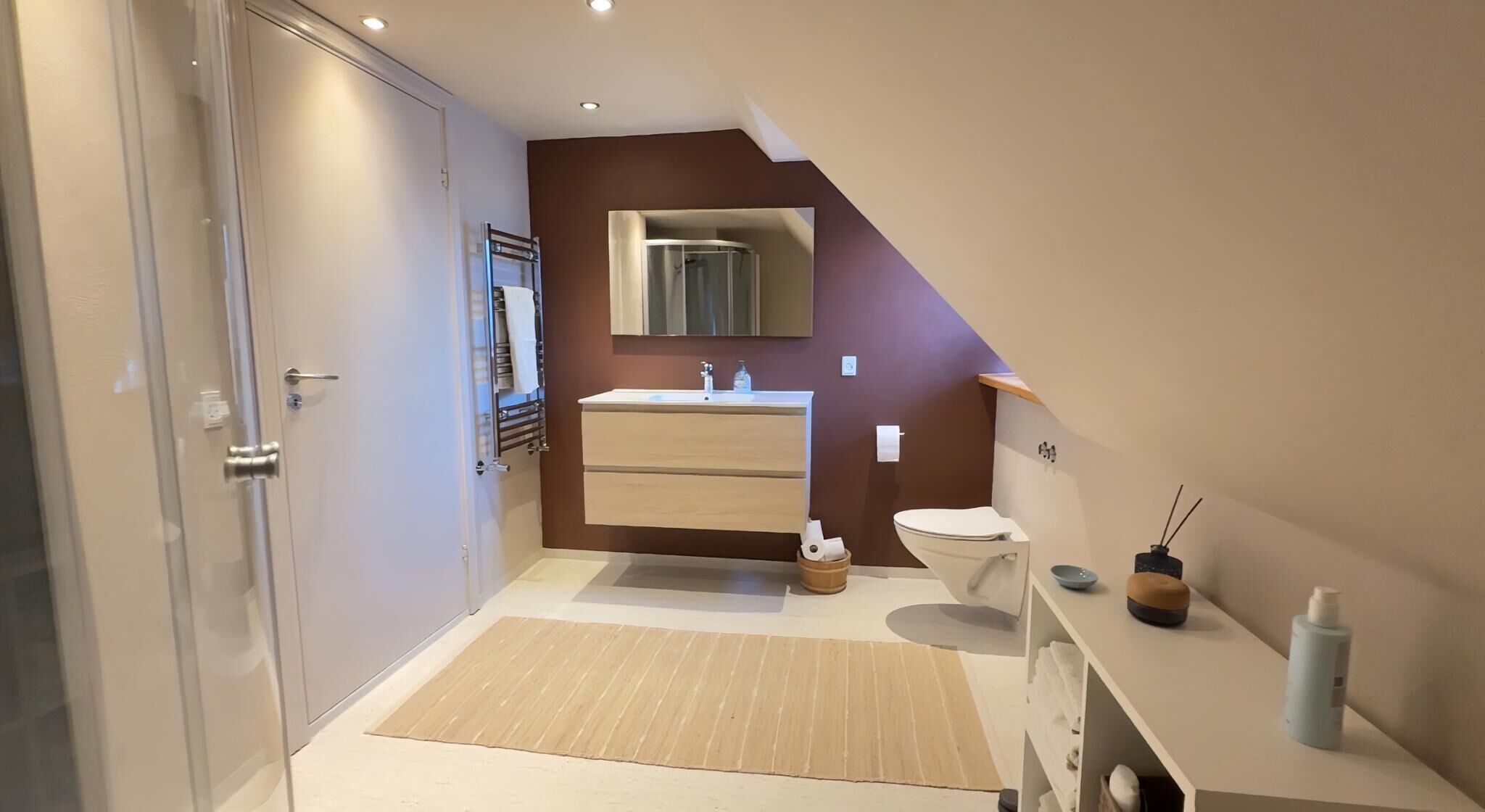 A modern bathroom with a shower, toilet, sink, and a mirror above the sink.