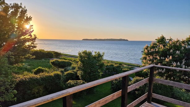 Eine Holzterrasse mit Blick auf das Meer und das entfernte Land.