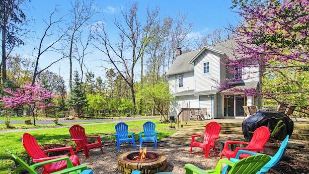 A patio with Adirondack chairs, a fire pit, and a house in the background. - Retreat with fire pit, walking distance to beach (Douglas)