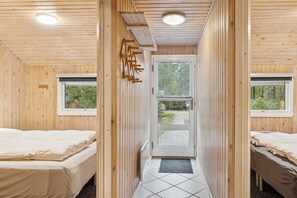 A room with two beds, a wooden ceiling, a door with a window, and a small window on the wall. - Holiday home with spa sauna and nature (Nørre Nebel)