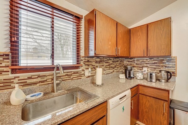 A kitchen with wooden cabinets, a granite countertop, a stainless steel sink, and a window with blinds. - Close to Hospitals & Downtown: Cleveland Home (North Olmsted)