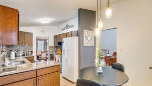 Eine moderne Küche mit Holzausbau, einer Granit-Arbeitsplatte und einem Essbereich mit rundem Tisch und Stühlen.