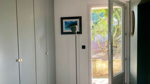 Ein Zimmer mit einer Schiebetür, die zu einem Außenbereich führt, einer Stehlampe und einem gerahmten Bild an der Wand.