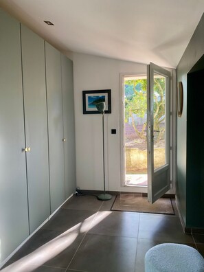 Une pièce dotée d’une porte coulissante donnant sur un espace extérieur, d’un lampadaire et d’un tableau encadré accroché au mur.