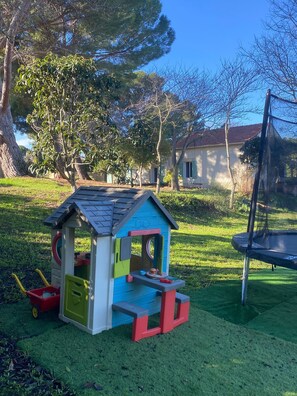 Une cabane de jeu avec un toboggan et une petite table avec des jouets.