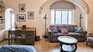 Een gezellige woonkamer met een bank, een bijzettafeltje, een bureau en een boekenplank.