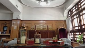 A room with a chandelier, wooden paneling, a glass cabinet, and a large window with curtains. - Hotel Astoria (Buenos Aires)