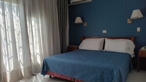 A hotel room with a bed, curtains, an air conditioning unit, and two wall-mounted lamps. - Hotel Astoria (Buenos Aires)