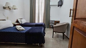 A hotel room with two beds, a chair, a small table, a TV, and a window with curtains. - Hotel Astoria (Buenos Aires)