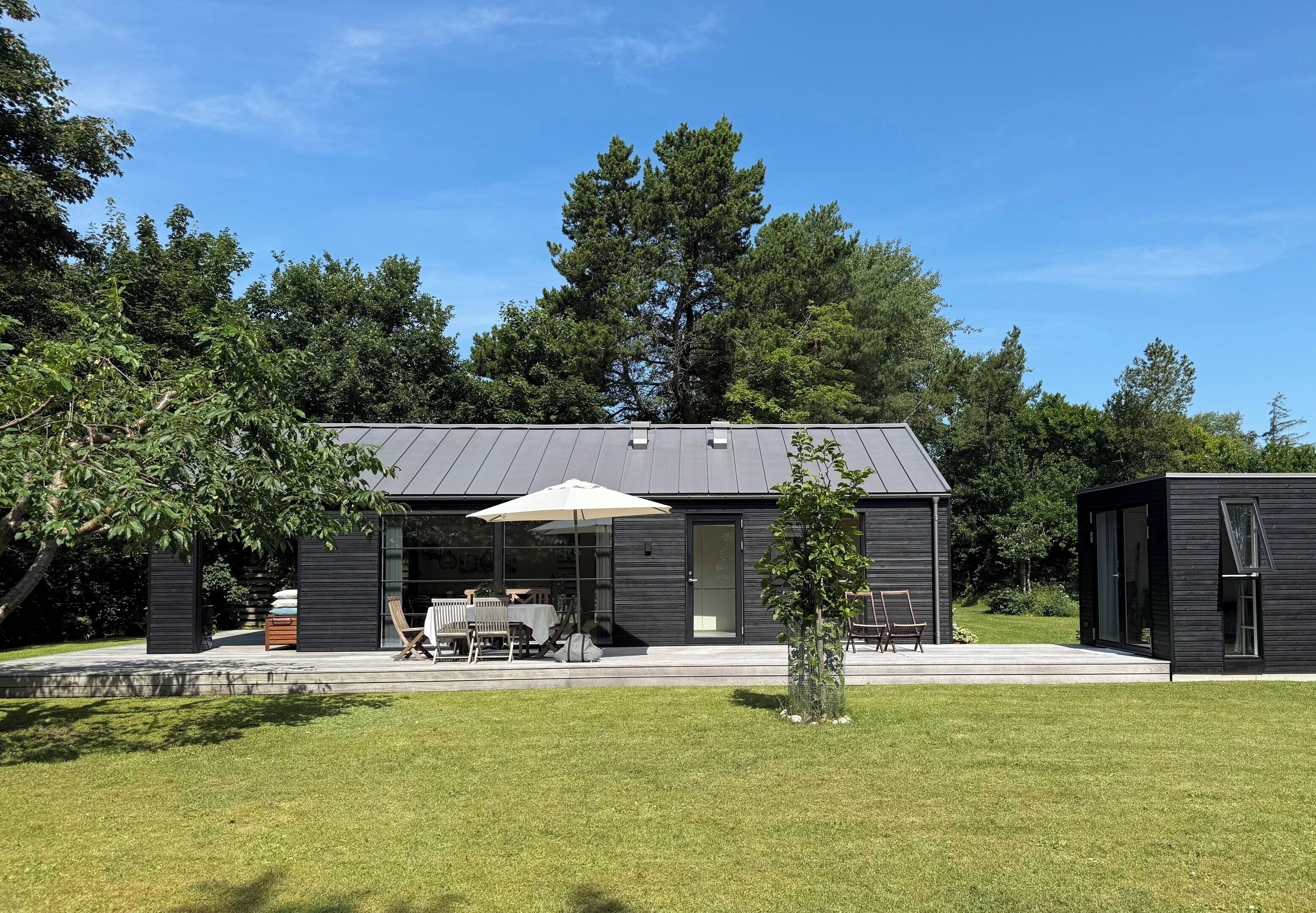 A modern house with a patio, a table, and chairs.
