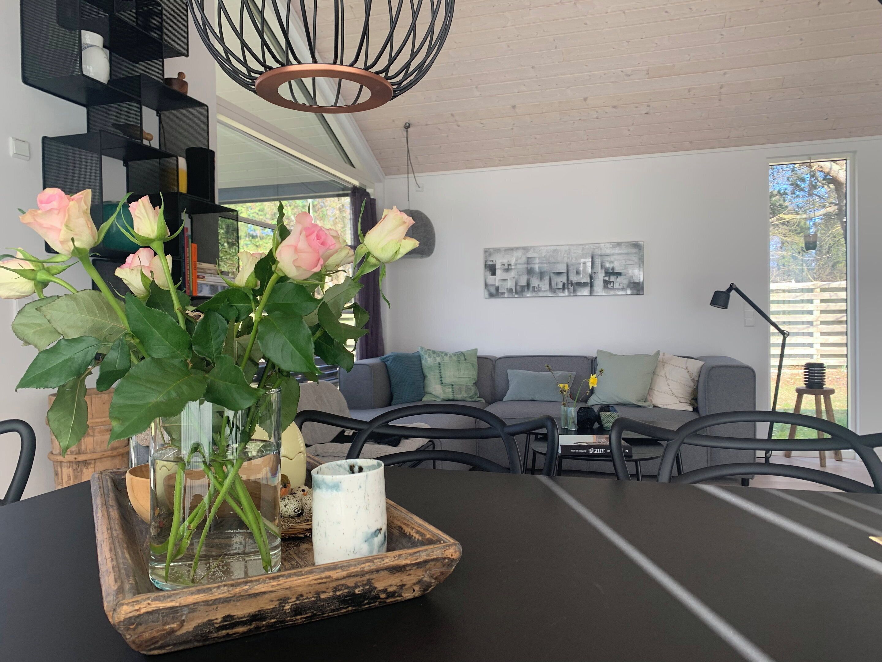 A modern living room with a sofa, coffee table, and chairs. There is a vase with flowers on the table.