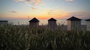 Una playa con cabañas de rayas y una puesta de sol.