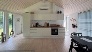 Una cocina moderna con armarios blancos, encimera de madera y horno empotrado.
