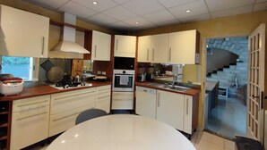 A modern kitchen with white cabinets, a central island, and a built-in oven. - F3 air-conditioned villa between the sea and Montpellier (Lattes)