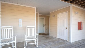 A porch with two white rocking chairs, a door, and a mailbox. - The Driftwood: Efficiency Suite in St. James with Pool! (Southport)