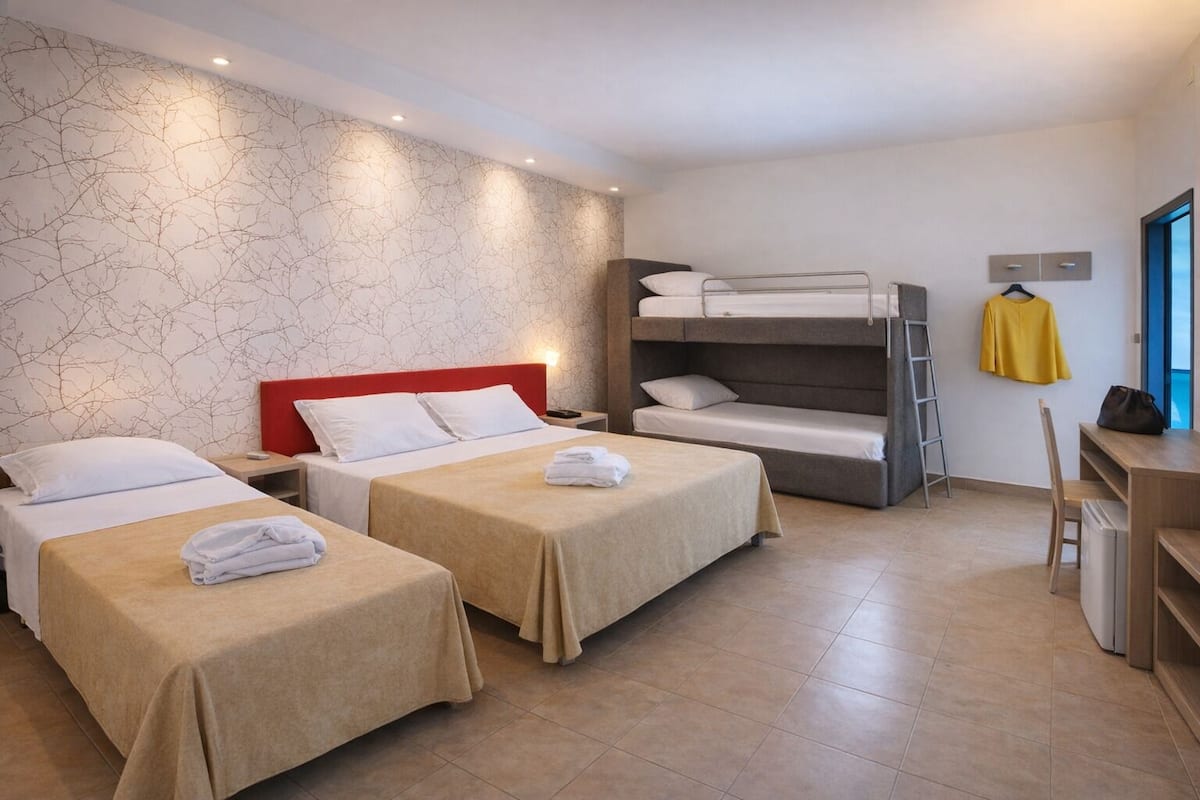 Una habitación de hotel con dos camas, una litera, un escritorio y una silla.