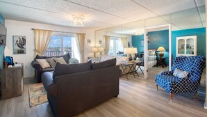 A modern living room with a sofa, armchair, and a dining area with a table and chairs. - King`s Getaway Oceanview Pool (Daytona Beach Shores)