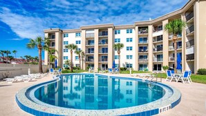 A hotel with a swimming pool surrounded by lounge chairs and palm trees. - King`s Getaway Oceanview Pool (Daytona Beach Shores)
