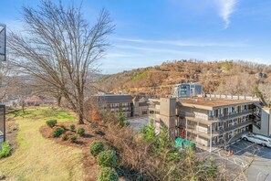A multi-story building with a parking area and a view of a hilly landscape. - 2BR Gatlinburg condo, walk to the strip! (Gatlinburg)