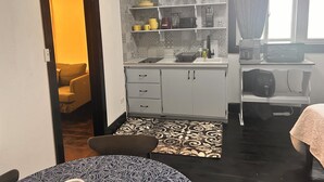Una cocina compacta con armarios blancos, microondas y cafetera.