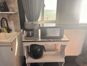 A kitchenette with a coffee maker, microwave, and a helmet on a small table. - Discounted Beachfront, Spacious Rental with Private Deck and Beautiful Views (Steventon)