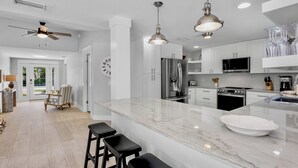 A modern kitchen with white cabinetry, a marble island, and stainless steel appliances. - C-View Florida: Canal Front Home w/ Dock! (Anna Maria)