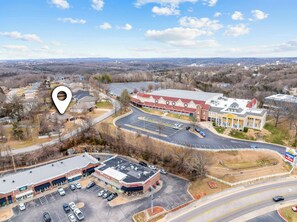 An aerial view of a commercial area with a parking lot, a large building with a red roof, and a smaller building with a green awning. - Dolly's House! In the heart of Branson! (Branson)