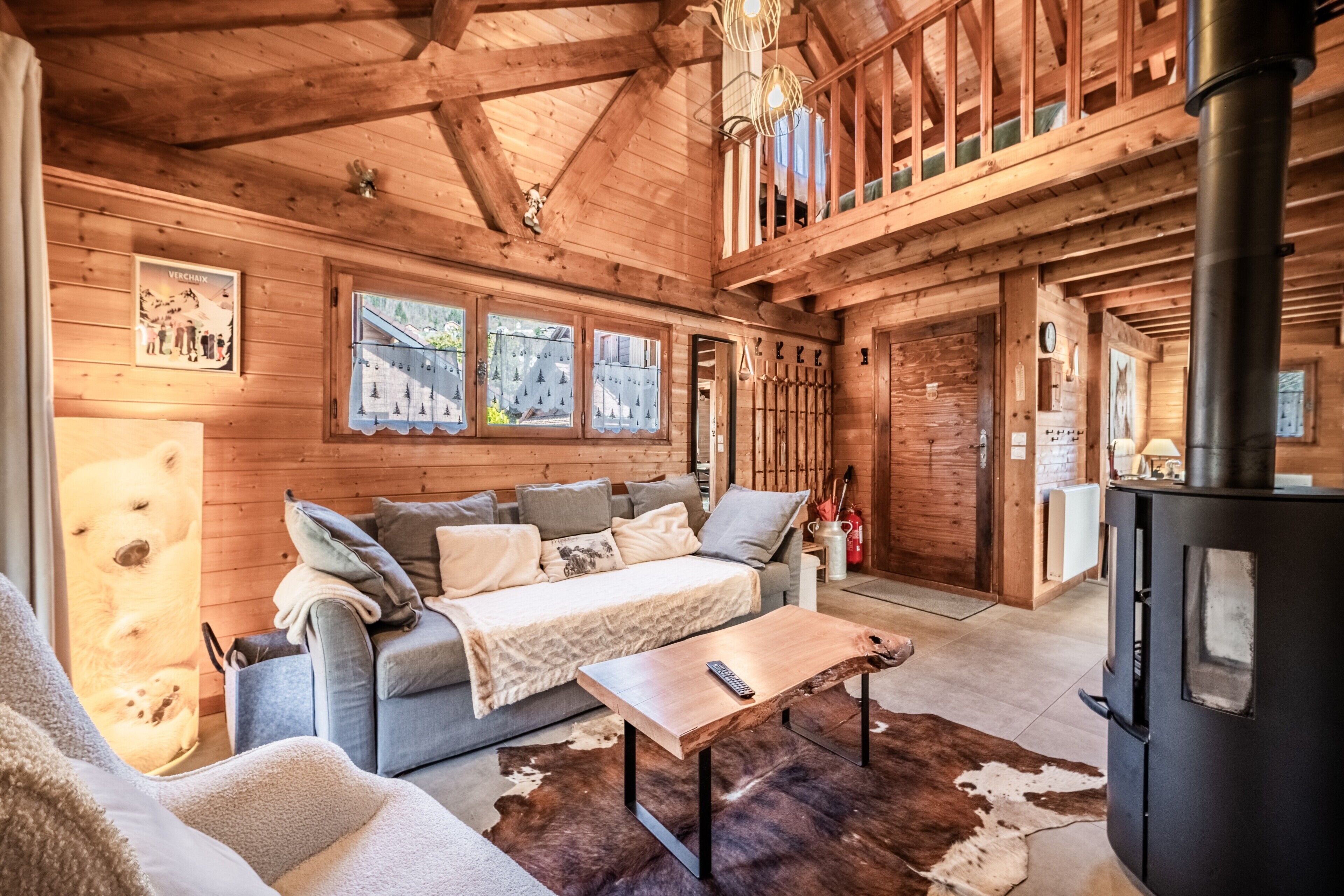 Un acogedor interior de cabaña con sofá, una mesa de centro, chimenea y techo de madera.