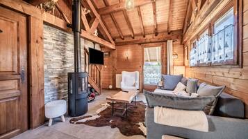 Ein Holzblockhaus-Innenraum mit Kamin, einer Couch, einem Fernseher und einer Steinwand.