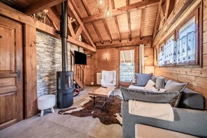 A wooden cabin interior with a fireplace, a sofa, a television, and a stone wall. - Chalet “6p Premium - Zibeline” with Mountain View, Private Terrace, and Wi-Fi (Verchaix)