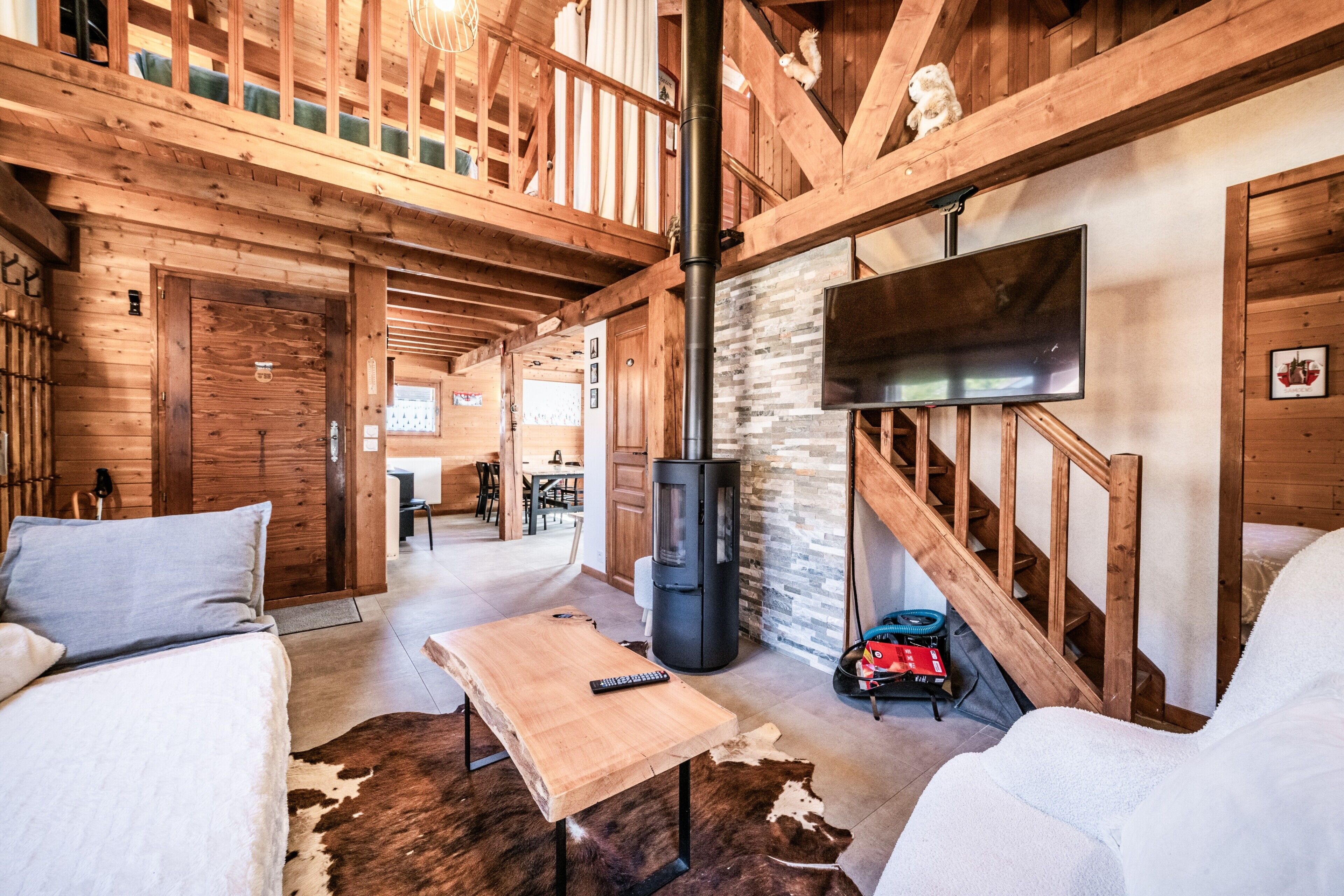 A wooden interior with a sofa, a table, a fireplace, and a TV.