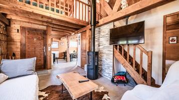 A wooden interior with a sofa, a table, a fireplace, and a TV.