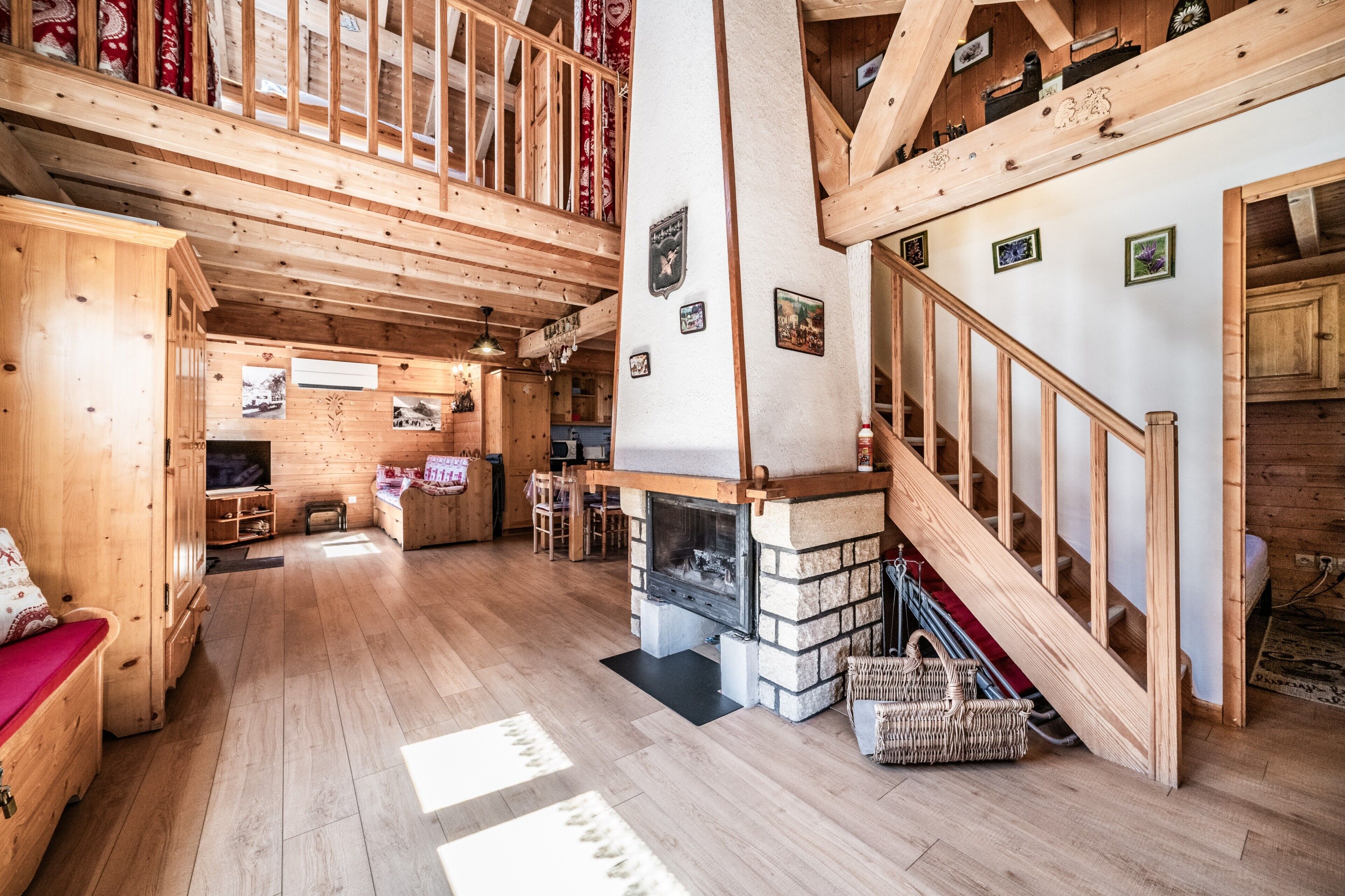 Un interno spazioso in legno, con camino, scala in legno e soffitto alto.