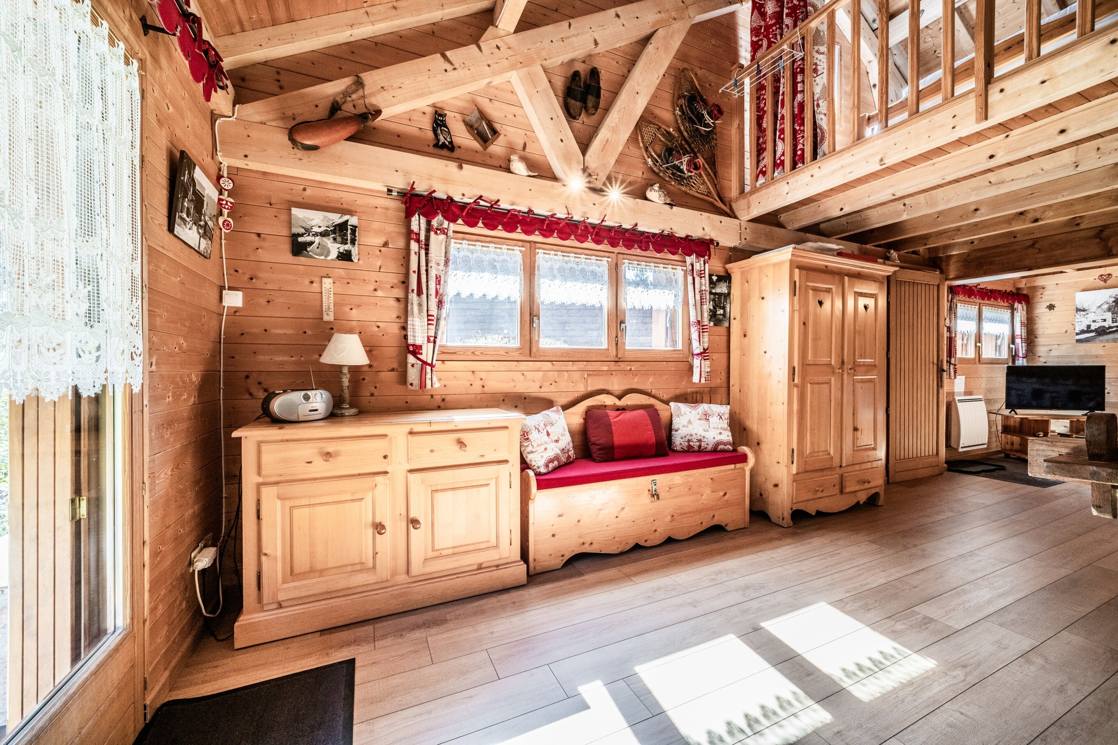 Interno di una baita in legno con una panca, un televisore e un camino.