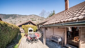 Een houten chalet met terras, buitenmeubels en een open haard.