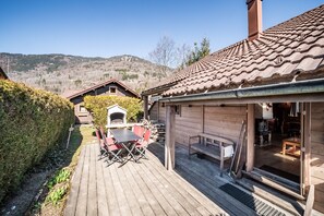Eine Holzhütte mit einer Terrasse, Sitzgelegenheiten im Freien und einem Kamin.