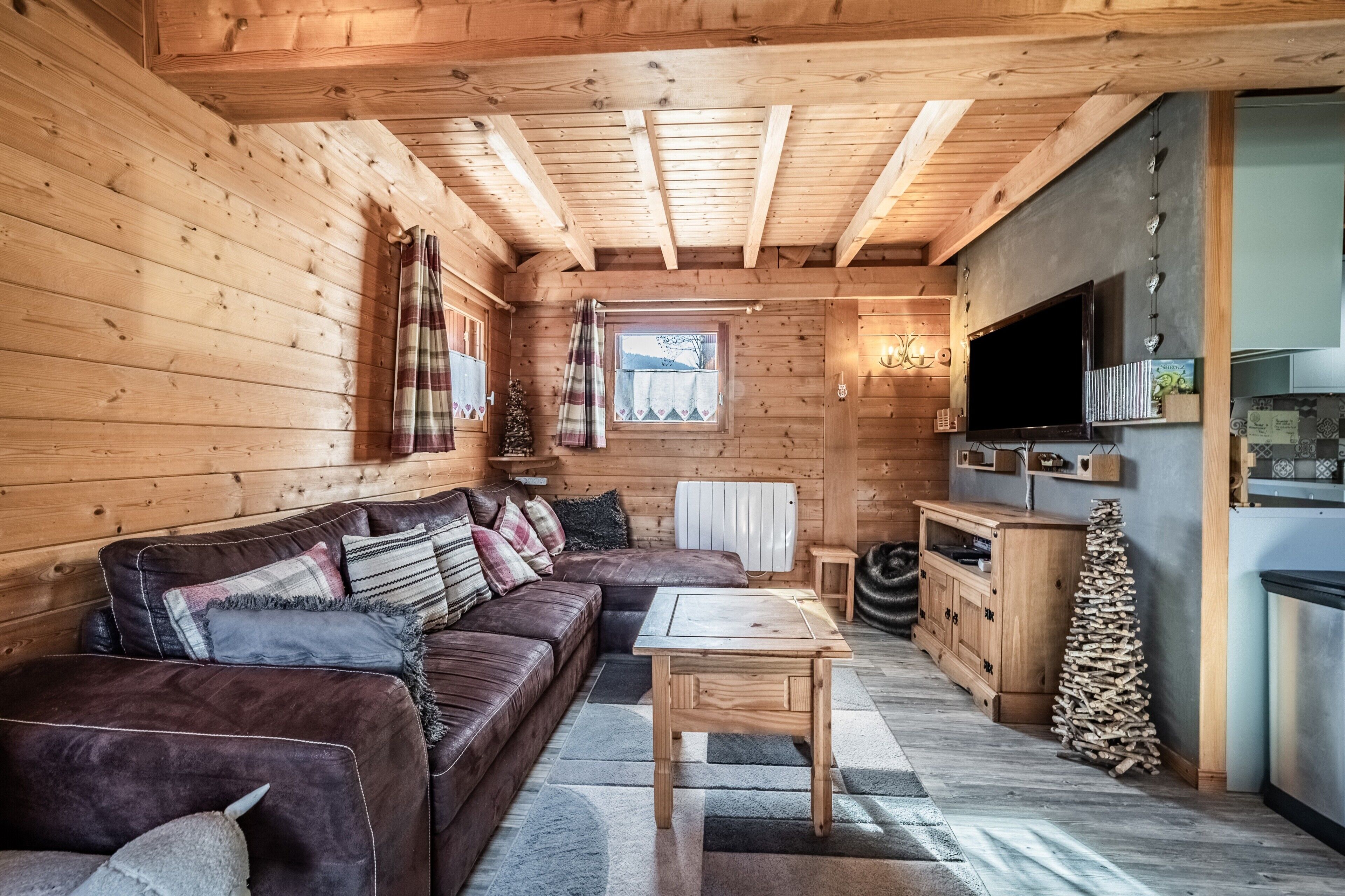 L’intérieur d’un chalet en bois comprend un canapé, une table, un coin cuisine et une fenêtre donnant sur un paysage agréable.