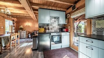 Een houten cabin met keuken, eethoek en uitzicht op de natuur.