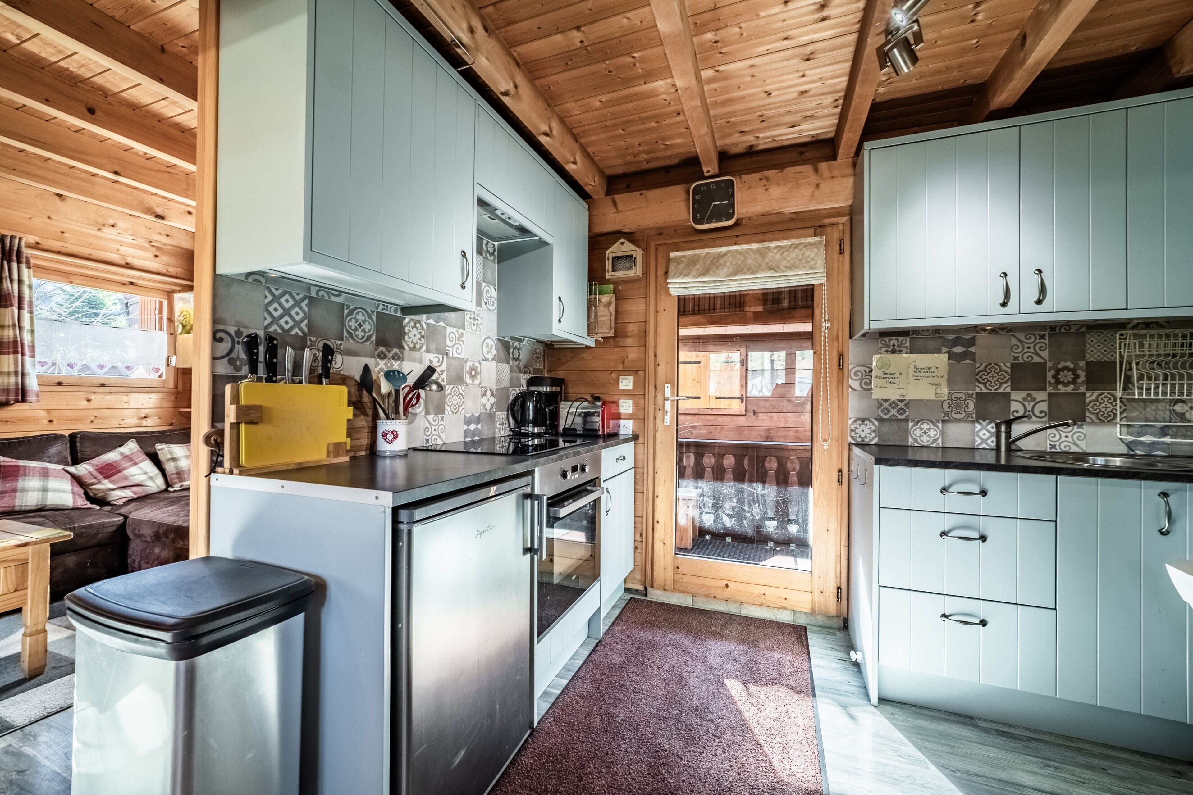 Een kleine keuken met houten kastjes, een koelkast, een fornuis en een wastafel.