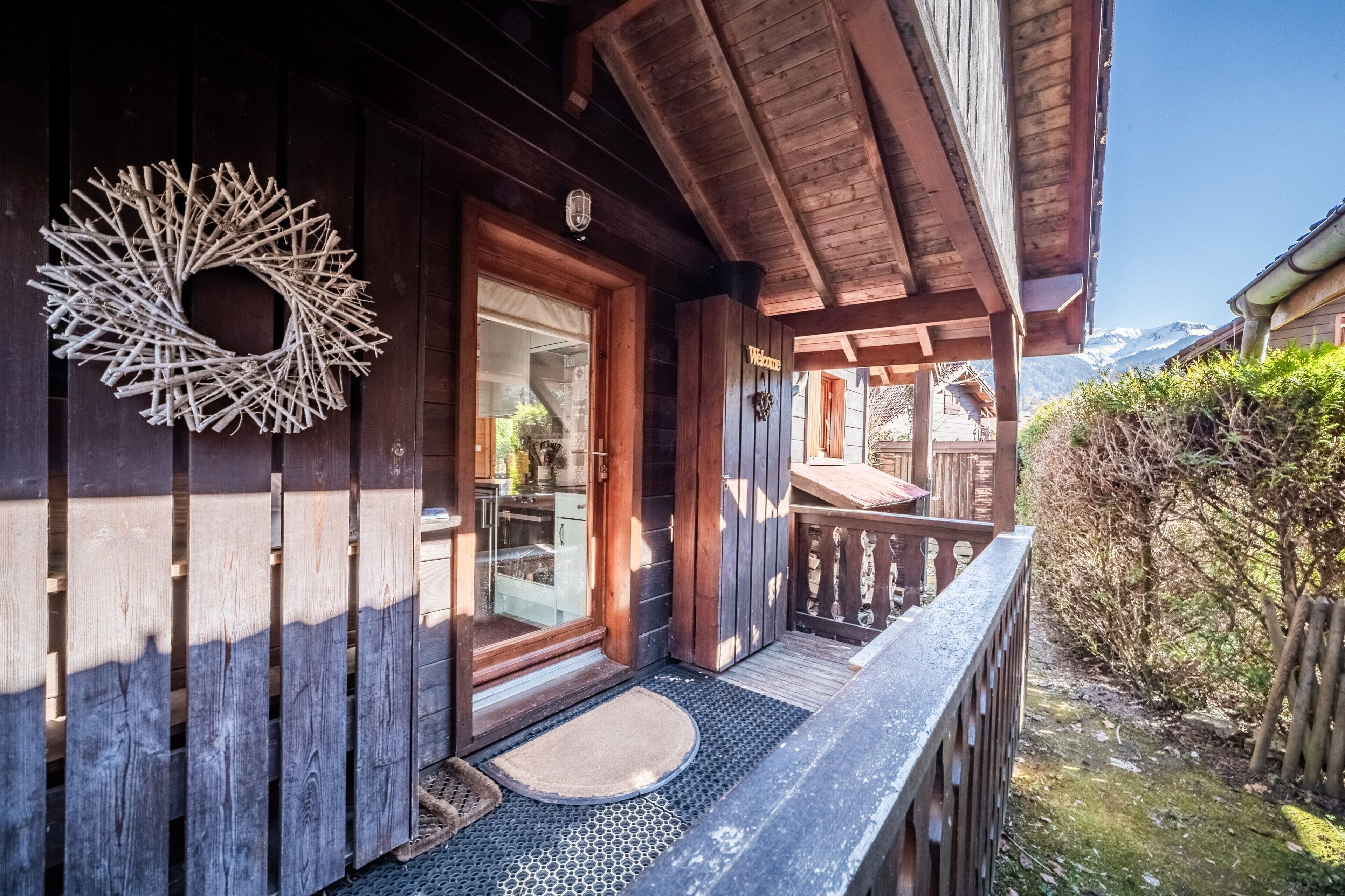 Un bâtiment en bois doté d’un balcon, une couronne de Noël en bois et un ciel dégagé.