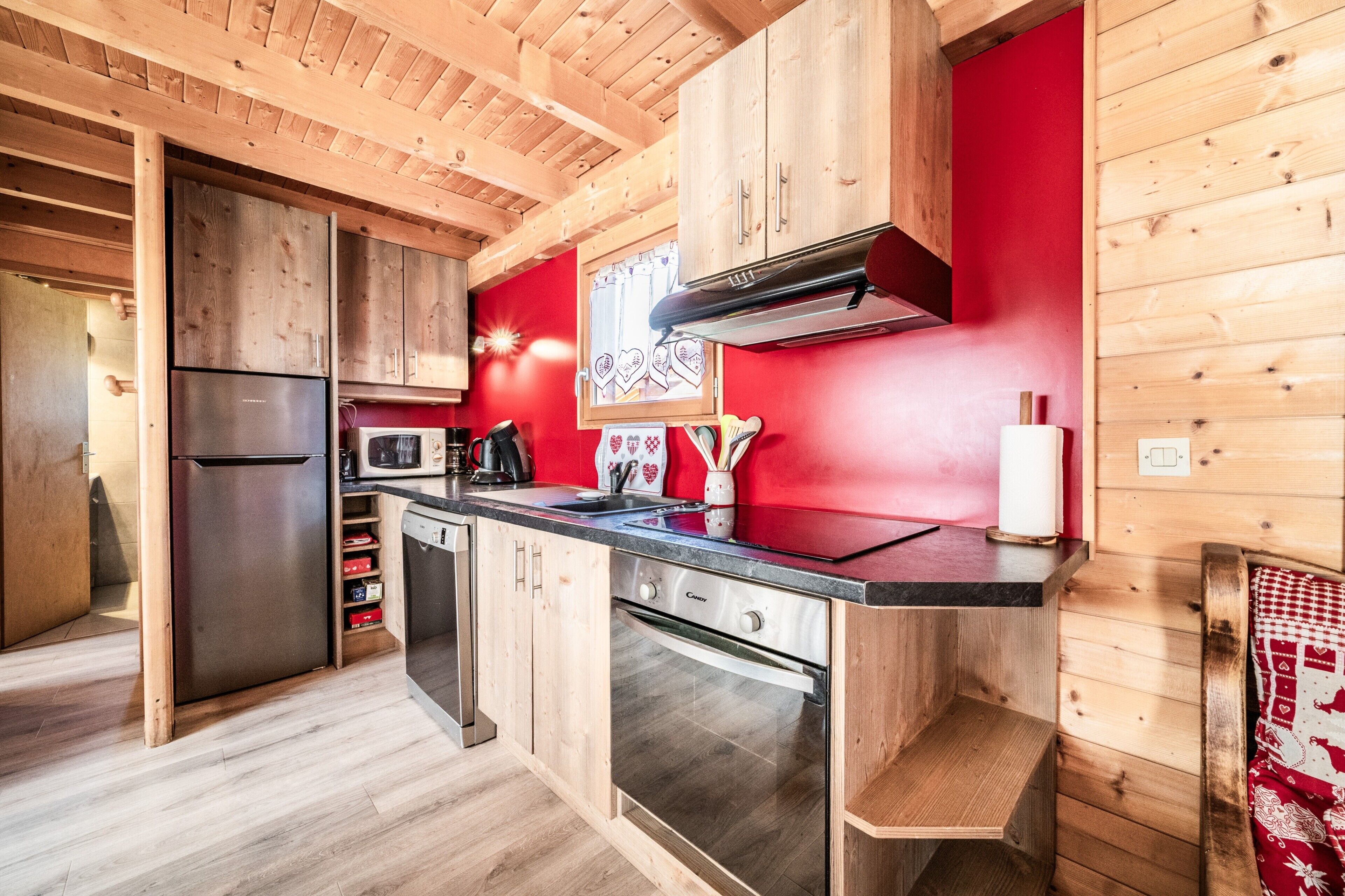 Una cucina funzionale con pensili in legno, un frigorifero in acciaio inossidabile, un forno a microonde ed una lavastoviglie.