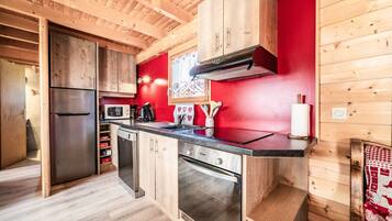 Una cucina funzionale con pensili in legno, un frigorifero in acciaio inossidabile, un forno a microonde ed una lavastoviglie.