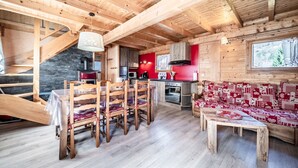 Un intérieur en bois comprenant un coin repas, une cuisine et un canapé rouge à motifs.