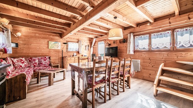 L’intérieur d’un chalet en bois comprend une table à manger, des chaises, un canapé et un coin cuisine.
