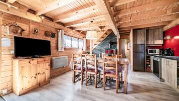 Un interior de madera con comedor, cocina y televisor.